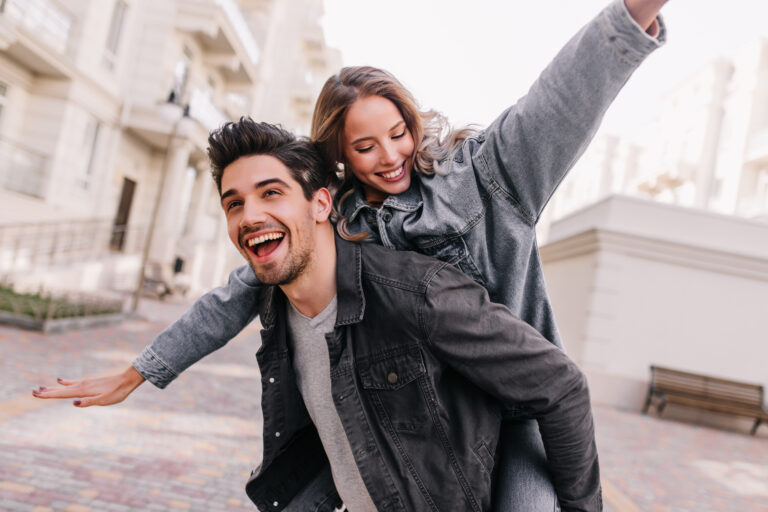Excited man in black denim jacket chilling with girlfriend. Outdoor photo of happy couple exploring city